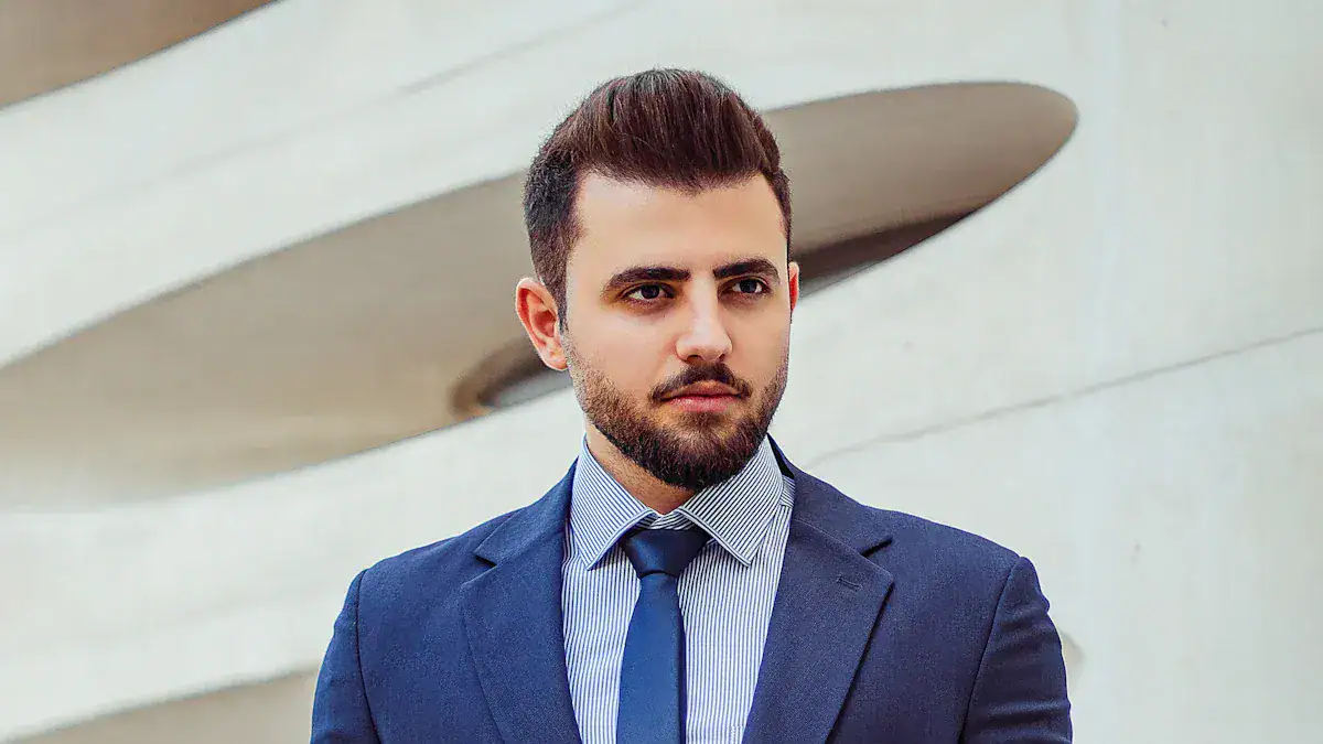 Polished young man in a navy suit and tie standing outdoors near modern architecture, emphasizing professional workwear for corporate uniforms.