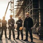 High-quality construction workers wearing safety gear and uniforms on a construction site at sunset, showcasing durable workwear designed for industrial and outdoor jobs.