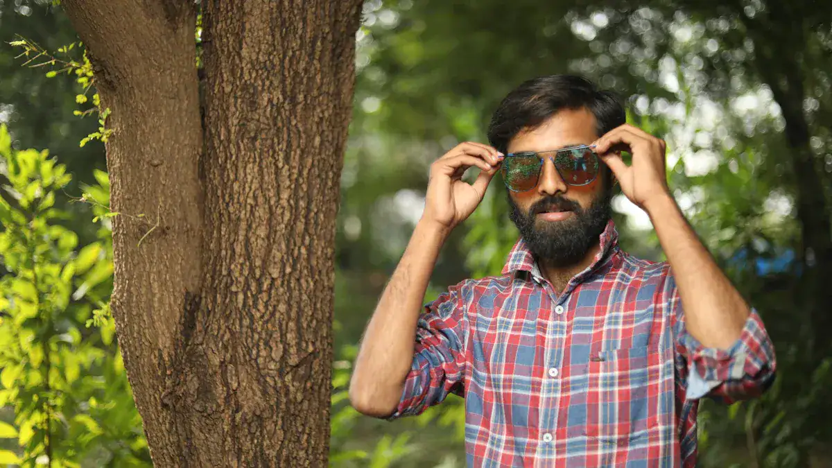 Vibrant outdoor scene featuring a man with sunglasses and a checkered shirt standing near a tree in a lush green park. Perfect for showcasing casual fashion or outdoor accessories.