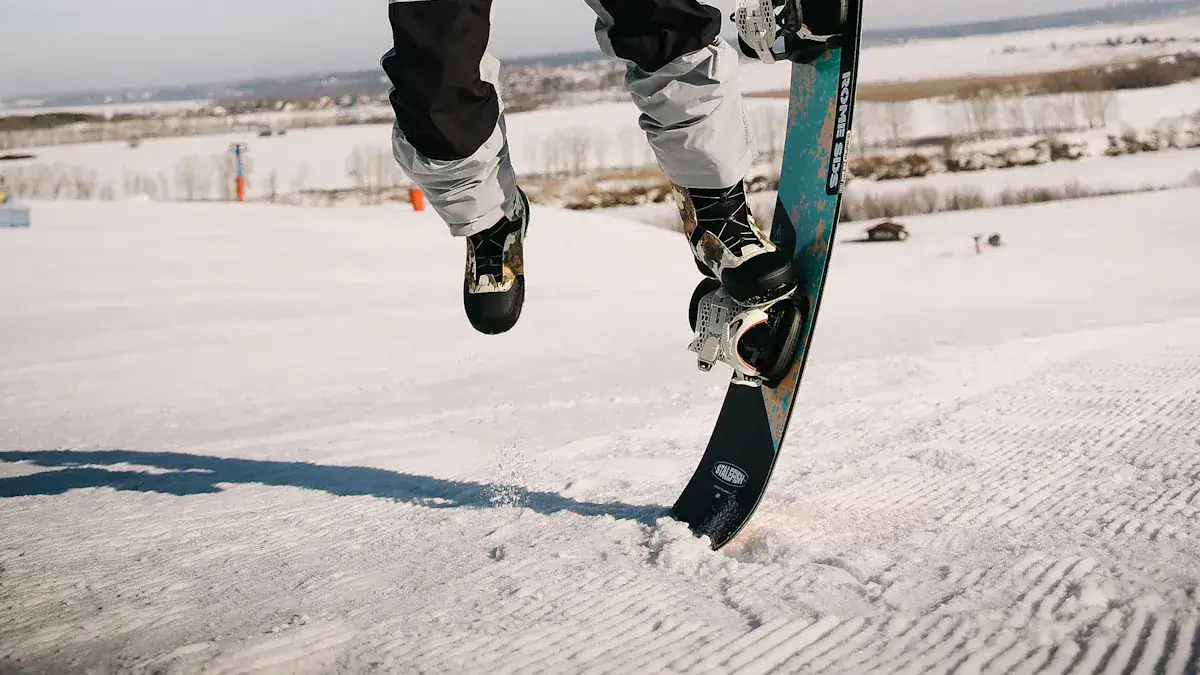 High-angle shot of a snowboarder performing a jump on a snowy slope, wearing insulated winter gear, with a clear winter landscape and distant mountains in the background.