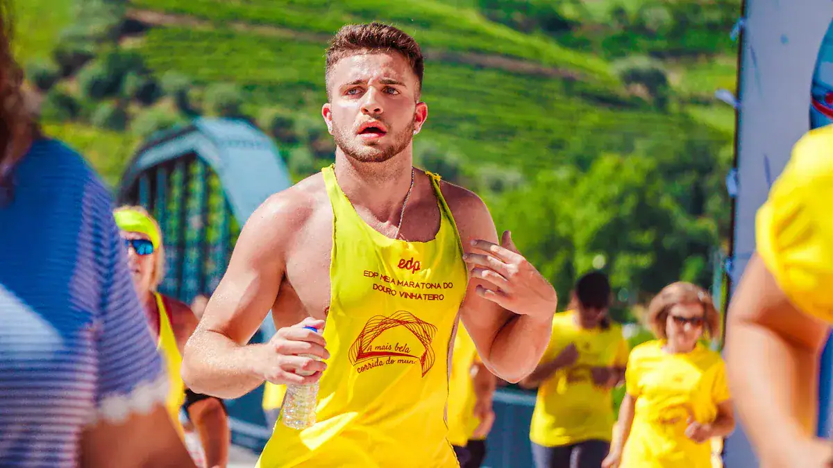 High-energy marathon runner wearing yellow custom athletic uniform during outdoor race in lush green countryside.