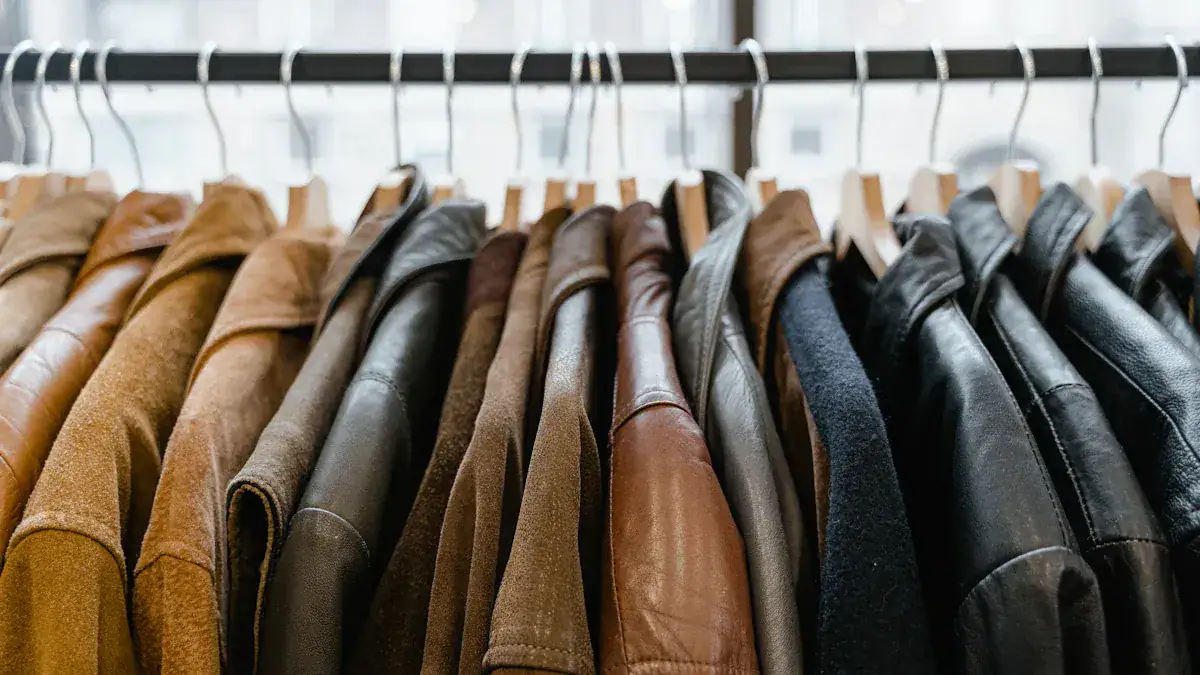 Luxurious leather and suede jackets hanging on wooden hangers in a clothing store display.
