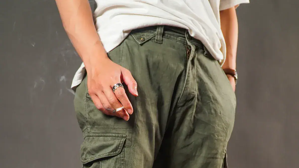Cargo pants with military green color and multiple pockets, styled with rings and accessories, suitable for casual or workwear settings.