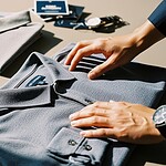 Bold, professional workwear polo shirts in grey, navy, and sky blue, neatly folded with tags visible, suitable for custom branding and corporate uniforms.