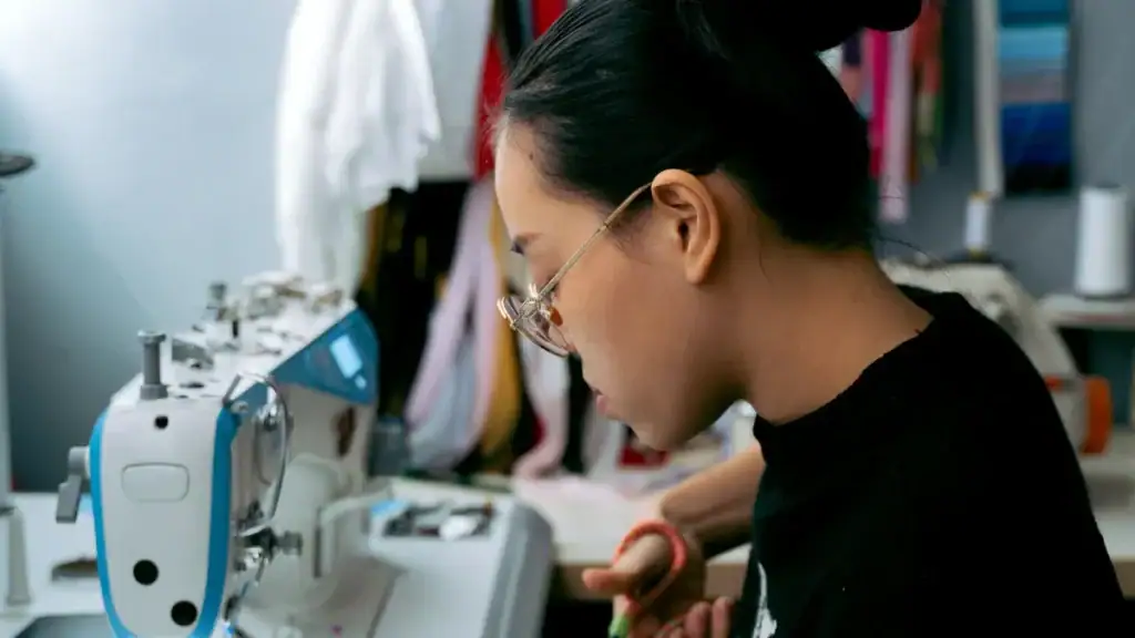 Sewing professional woman working at a textile machine in a clothing manufacturing facility in China.