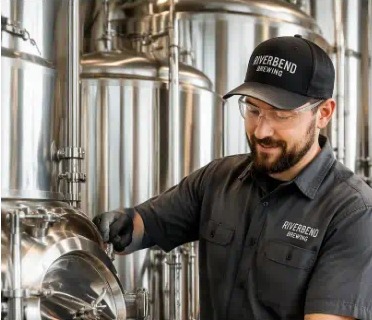 Adult taproom staff serving customers in branded brewery workwear