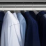 Corporate navy polo shirts with subtle chest embroidery on hangers in a clean factory showroom